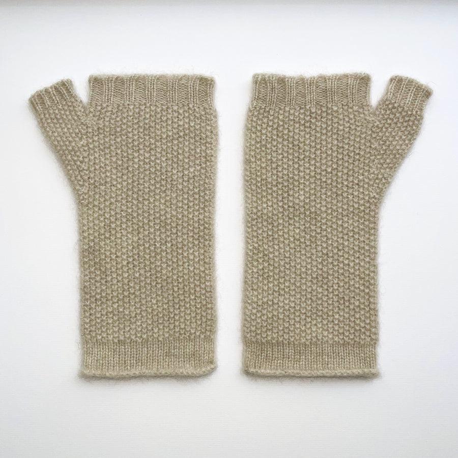 Pair of beige knitted fingerless gloves with a label on a white background