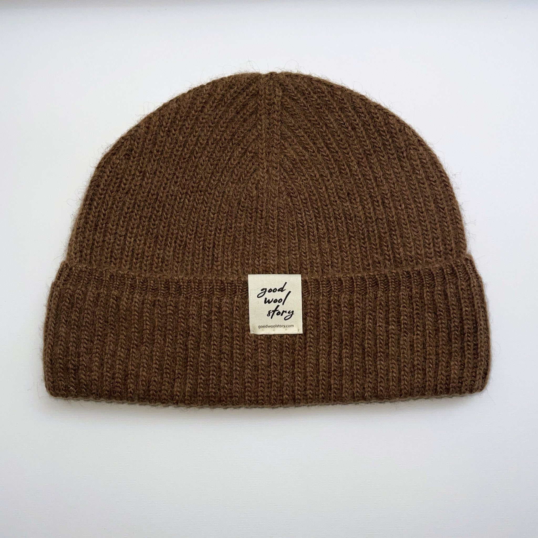 Camel brown knit beanie with a label on a white background