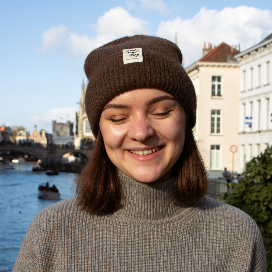 Dark brown beanie with a white label on a black background