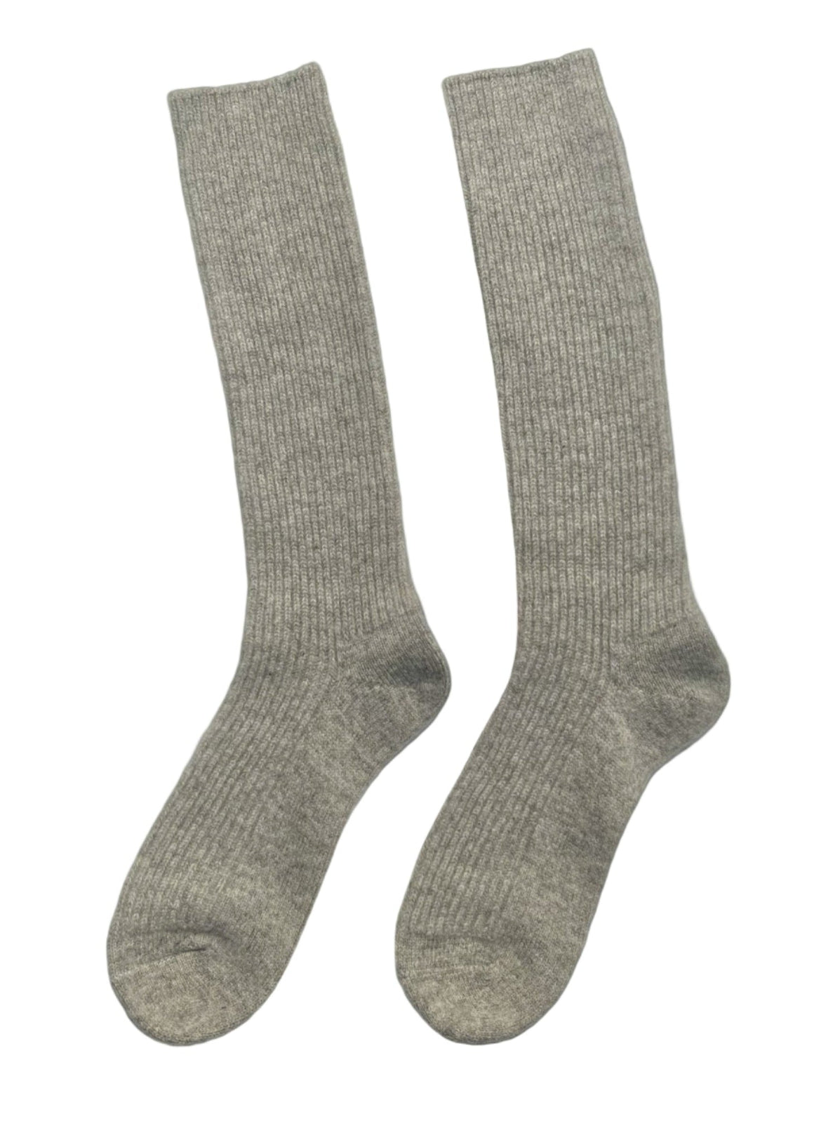 Beige knee-high socks worn by a person on a white background with a green leaf.