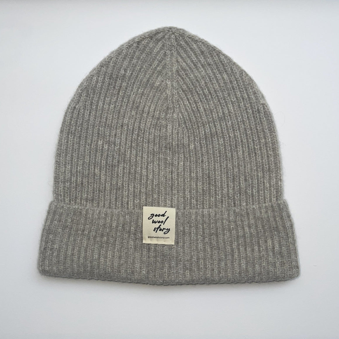 Gray knit beanie with a label on a light gray background