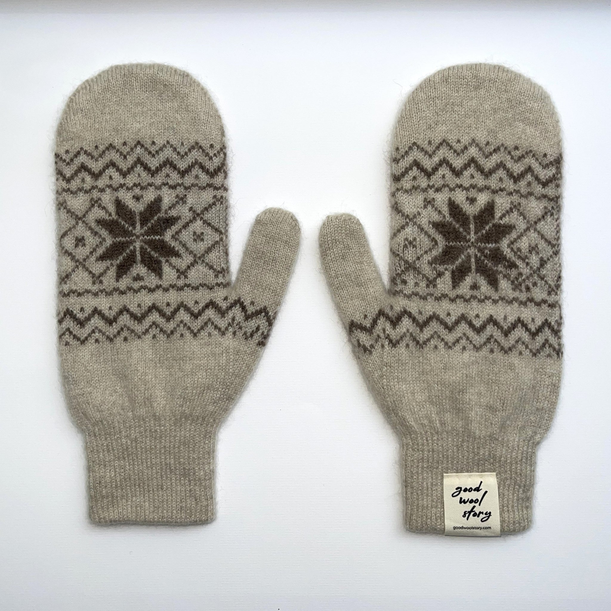 Pair of cream coloured knit mittens with patterned design on a white background