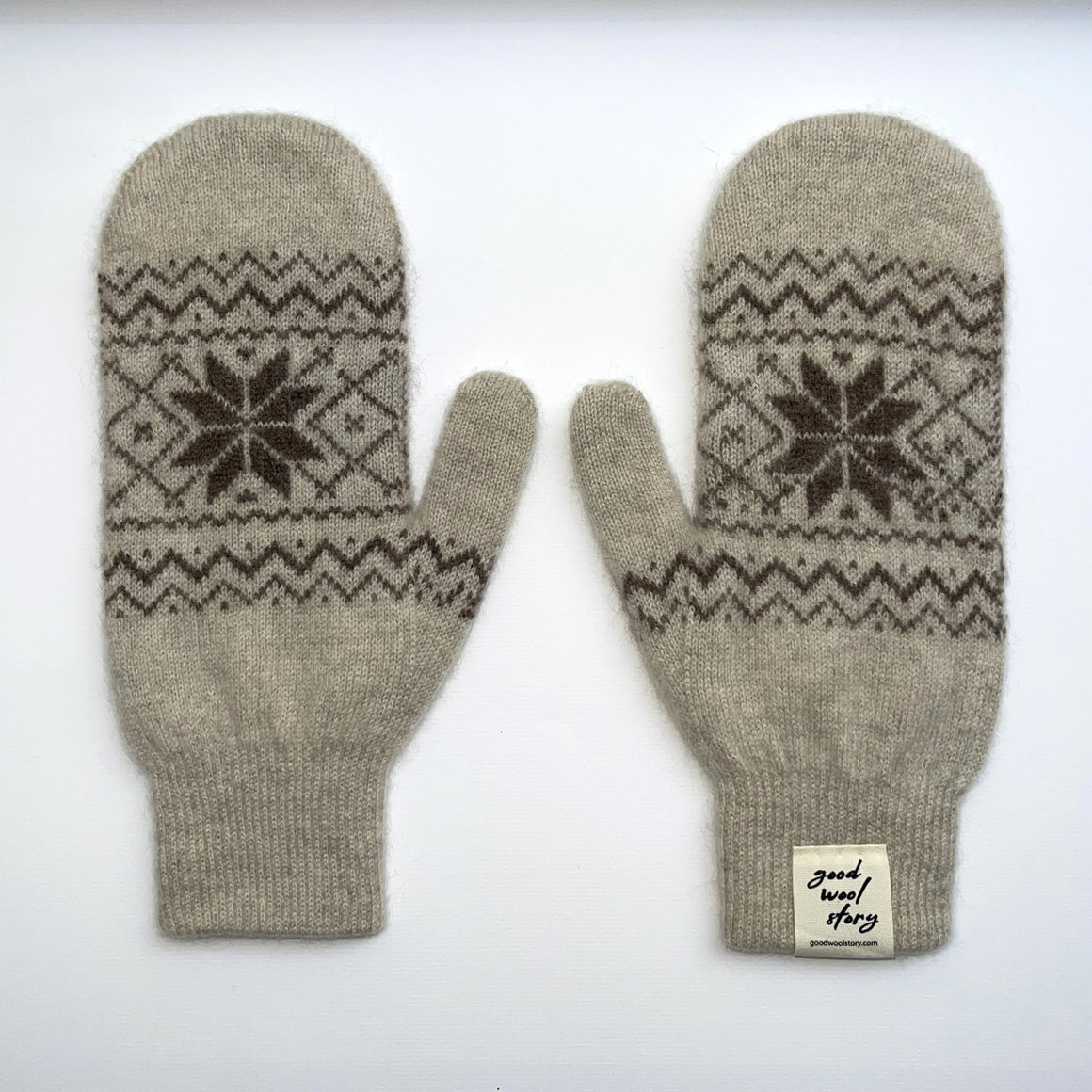 Pair of cream coloured knit mittens with patterned design on a white background