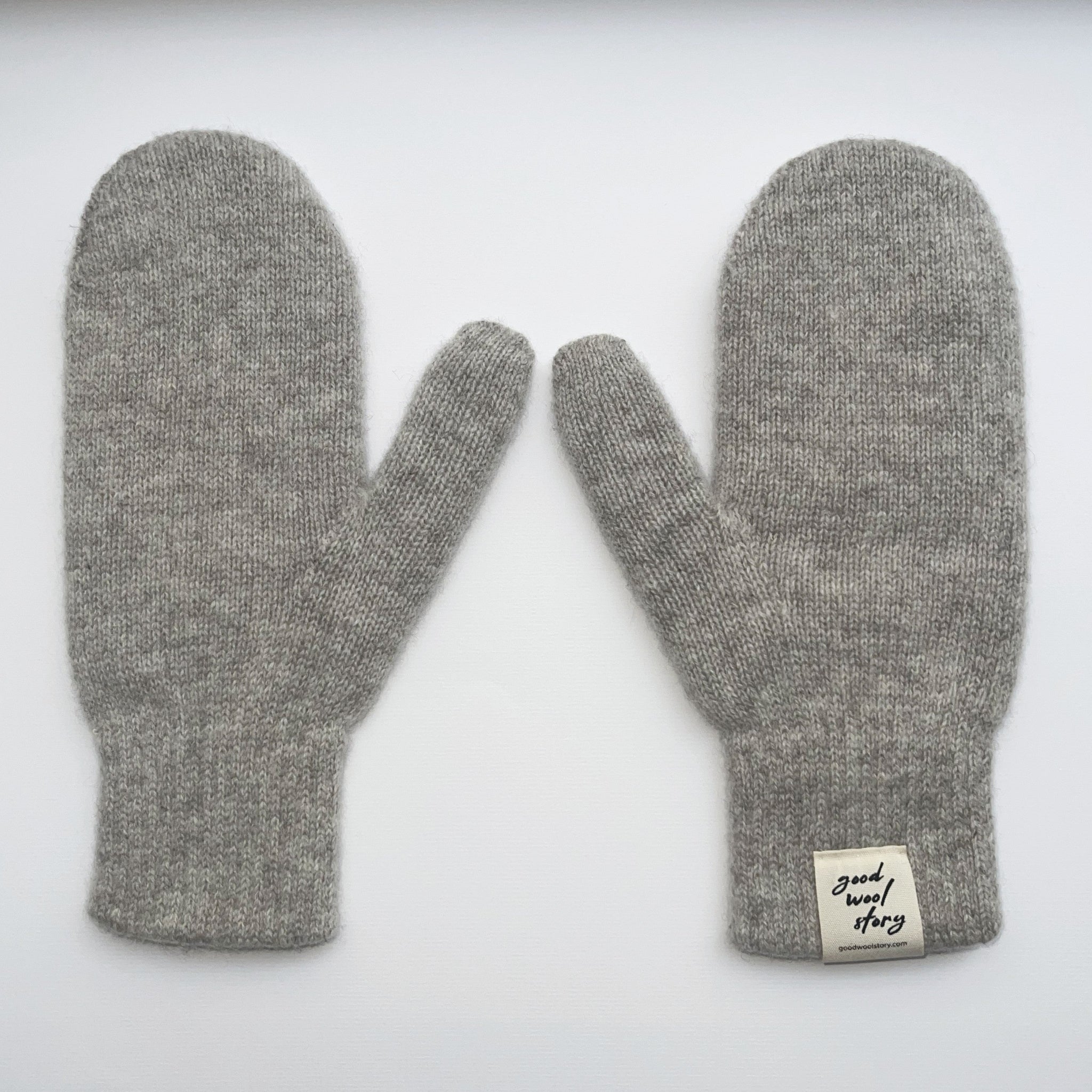 Pair of gray mittens with a label on a white background