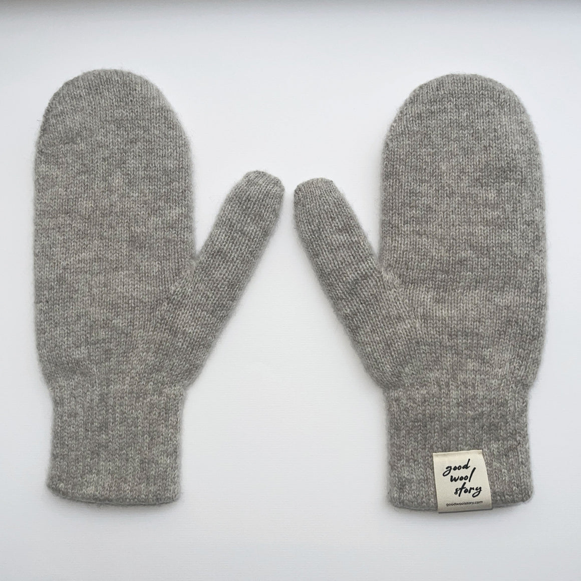 Pair of gray mittens with a label on a white background